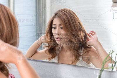 近距离的微笑女人化妆刷近脸和看镜子。亚洲美女