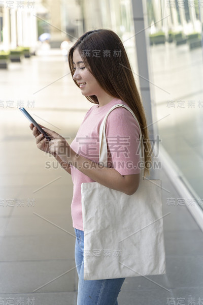年轻漂亮的女人拿着一个白色的帆布包