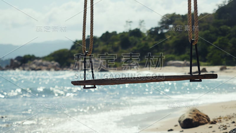 热带岛屿海滩和树秋千。在美丽的背景下，海浪拍打着大海中的石头。苏梅岛的天堂