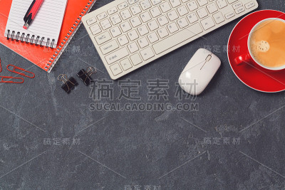 有电脑、笔记本和咖啡杯的办公桌，背景是黑板。俯视图