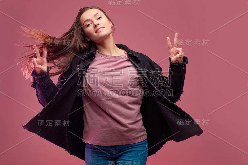 粉红色背景上的年轻褐发女人。工作室肖像，非正式的服装风格，