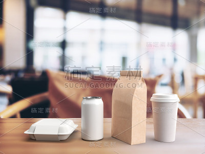 一个外卖午餐盒，饮料罐，纸咖啡袋和咖啡杯的白色模型的3d渲染在一个模糊的餐厅背景木桌上