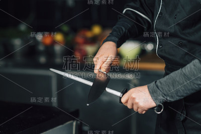男厨师在厨房里磨刀