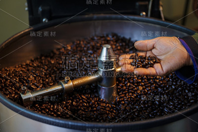 女人的手拿着新鲜烤咖啡豆在桶容器上