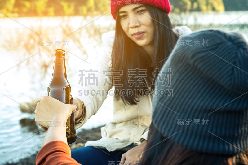 女人坐着喝啤酒放松假日与美丽的自然。