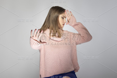一个年轻女性的肖像穿着粉红色毛衣与停止手势