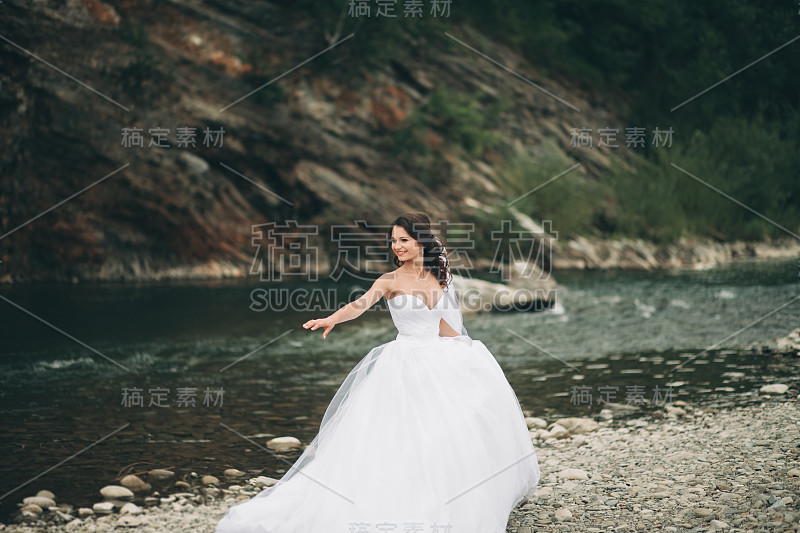 美丽奢华的年轻新娘在长长的白色婚纱和