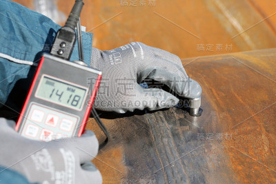 检验员正在用测厚仪测量管材的壁厚。