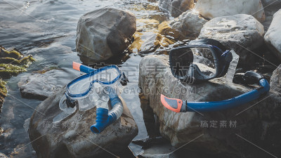 潜水面具和通气管躺在石头上，在海上背景。旅游自由潜水概念