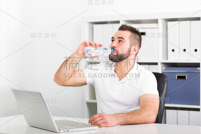 英俊的年轻人喝瓶子里的水