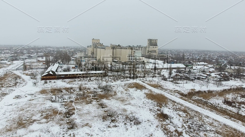 谷物在冬季终了。农村地区被雪覆盖的粮食升降机。干燥和储存谷物的建筑物。