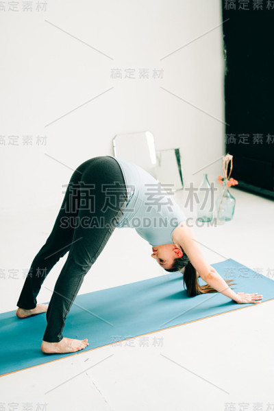 年轻怀孕女孩在运动服装做瑜伽，在工作室做asana Adho mukha shvanasana