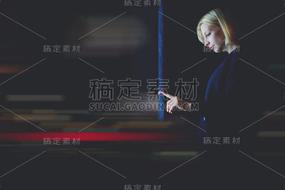白人女性站在城市的聚光灯下使用带有大数字屏幕的自动取款机，女性通过现代设备图标验证银行应用程序上的账