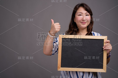 工作室拍摄的成熟美丽的亚洲女商人在灰色的背景
