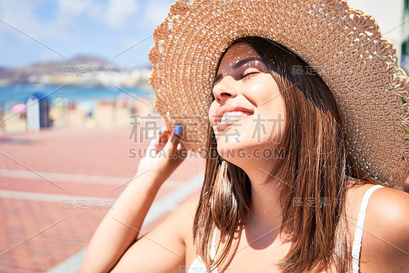 美丽的年轻女子走在海滩散步欣赏海景微笑愉快的暑假