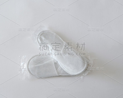 用透明包装的一次性新拖鞋躺在床单上