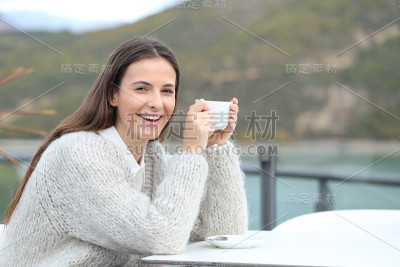 快乐的女孩拿着咖啡杯看着相机