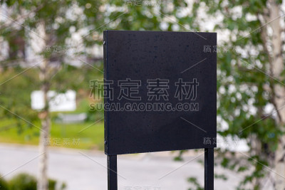 特写黑色金属标志在绿色草地的背景，铭牌与一个空间为您的文本，copyspace，空白空间的题字。