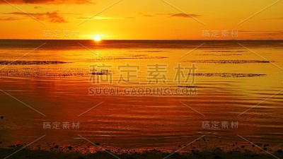 壮观的日落颜色倒映在塞班，北马里亚纳群岛的海滩水域。
