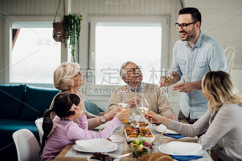 一个兴高采烈的人在餐桌上向家人敬酒。