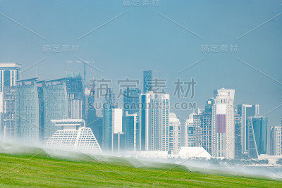 多哈的现代天际线全景与绿色草地前景。健康环境的概念