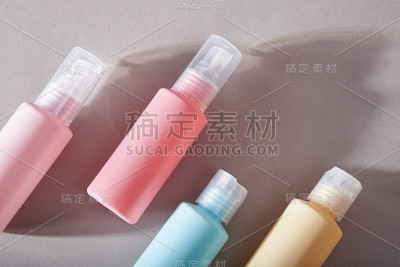 旅行装备。一套四个塑料瓶化妆品。带有阴影的灰色背景。