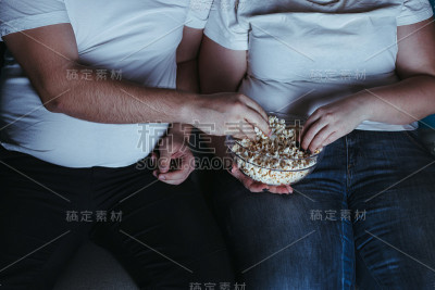 超重夫妇看电视吃垃圾食品