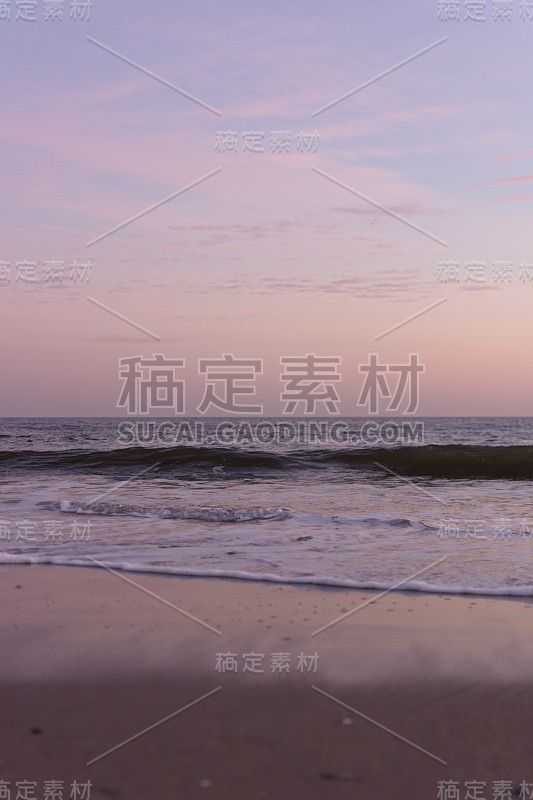 日落时，平静的海浪在海滩上翻滚