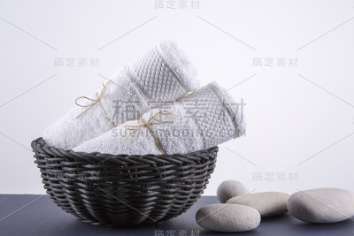 两条白毛巾放在黑篮子里。背景是白色的。
