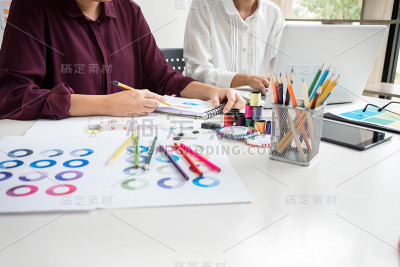 两个年轻的服装设计师或设计师同事作为时装设计师和绘制服装草图，选择颜色条在平板，职业和职业职业，时尚