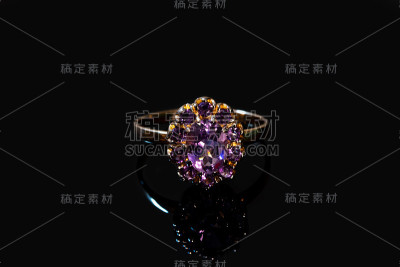 美丽的金色戒指与紫色宝石孤立在黑色背景