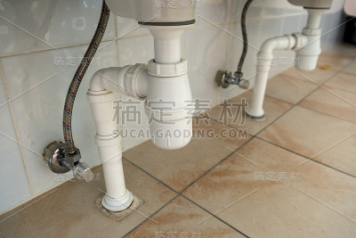 浴室洗涤槽下白色塑料排水管的特写。