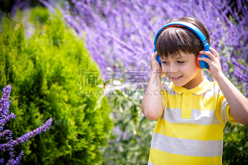 小男孩戴着耳机在大自然中听现代音乐。孩子喜欢这首歌。儿童音乐放松概念课后