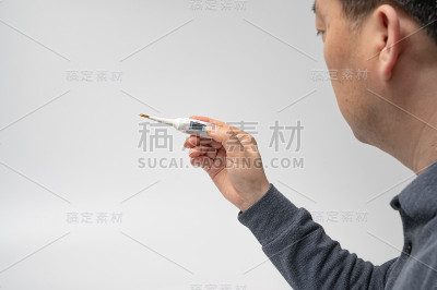 白色背景上，一只男性的手拿着一个数字温度计