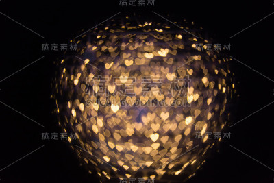 模糊的背景与心脏形状的金色光散景在黑色的背景。