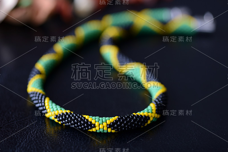 明亮的串珠牙买加项链在一个黑暗的背景近距离