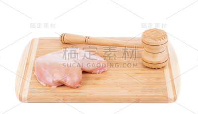 生鸡胸肉和木槌上的砧板。