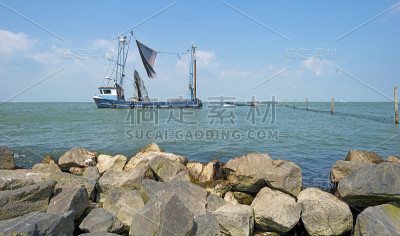 拖网渔船沿着堤岸在湖上捕鱼