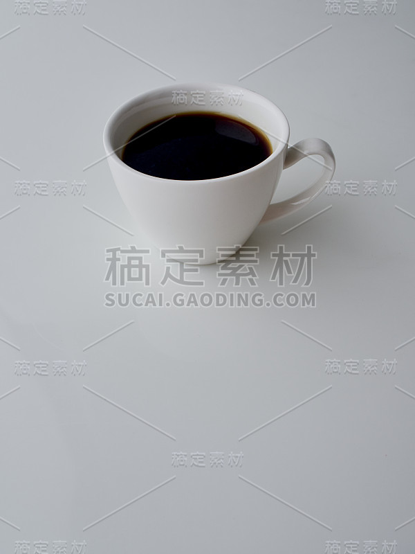 白色桌子上白色杯子里的热黑咖啡有烟