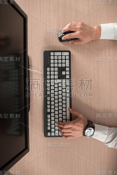 办公室的木桌桌上有电脑和周边设备。