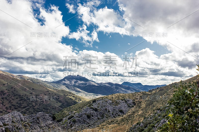 山景上的蓝色多云的天空背景。风景如画的群山在阳光下闪闪发光。令人屏息的自然影像