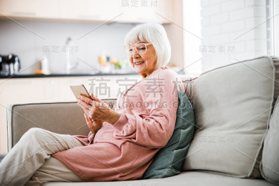 坐在沙发上玩手机的快乐老太太