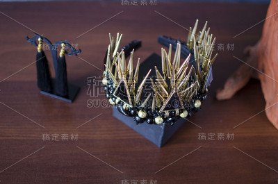 美丽的金色时尚皇冠与黑色宝石和刺。木桌上放着黑色的耳环和金色的王冠