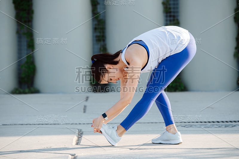 漂亮的女人伸展在混凝土路面上，做前弯