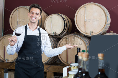 男售货员拿着酒杯在酒窖里卖酒