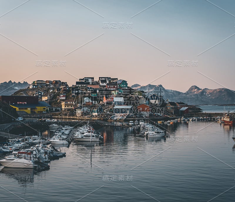 格陵兰岛马尼托克北极城市的日落景观。午夜太阳的背景是群山。色彩斑斓的房子和全景。查看港口与船只。