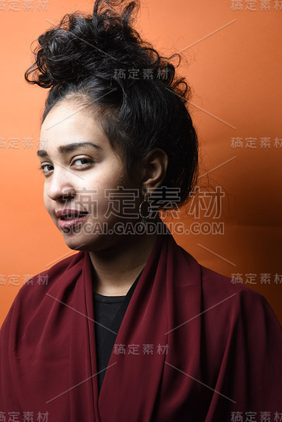 工作室拍摄的年轻美丽的埃及少女与黑色的头发与橙色的背景