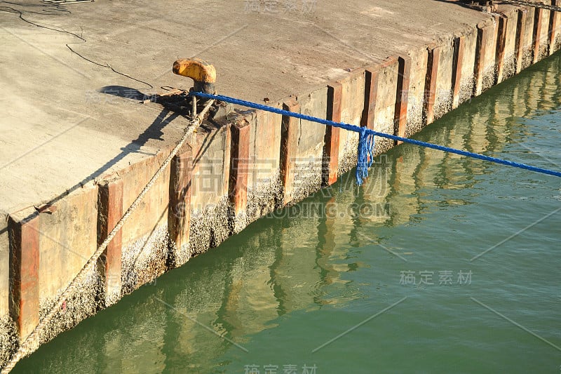 两根绳子系在码头系柱上的照片