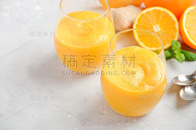 新鲜健康的冰沙与柿子，橙和姜在灰色混凝土背景。