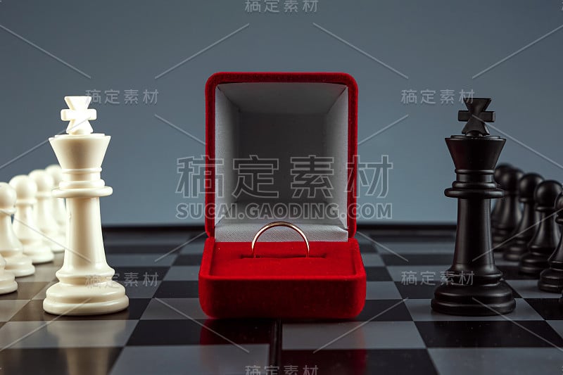 棋盘上的棋子和一个带金戒指的盒子，游戏。对抗、事业、竞争、创业、休战、婚姻、伙伴关系的概念。